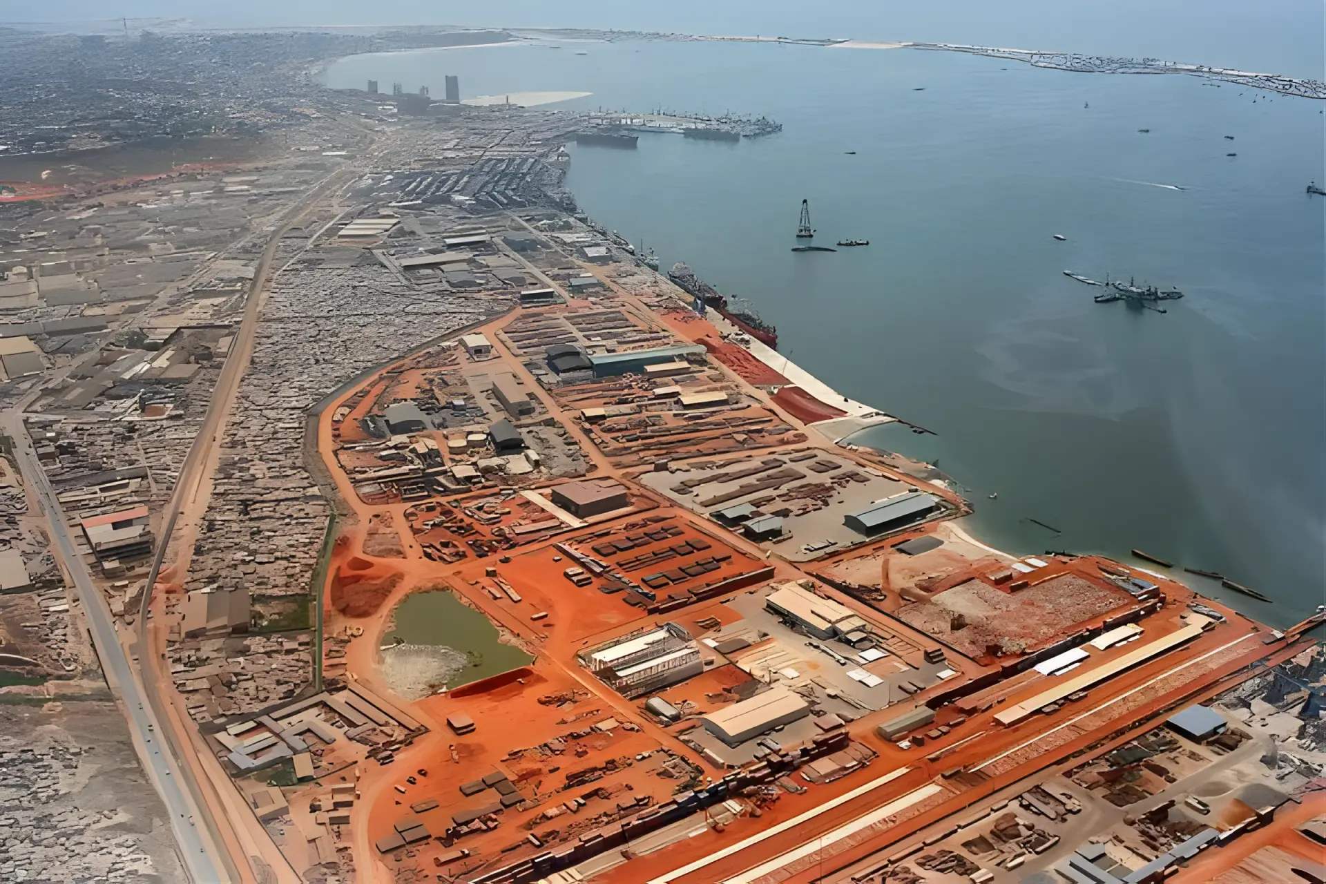 Vue aérienne des parcs logistiques, entrepôts et quais du côté nord du port de Luanda, avec des navires de ravitaillement dans la baie