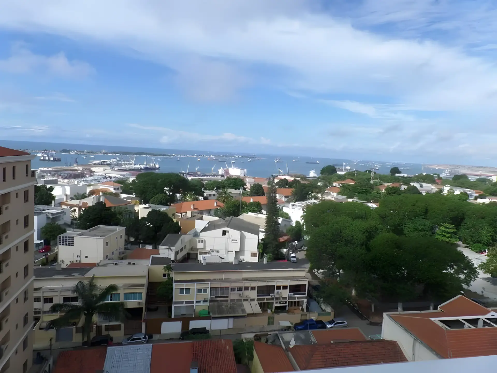 Vue depuis Miramar sur des toits arborés vers le port de Luanda et la baie