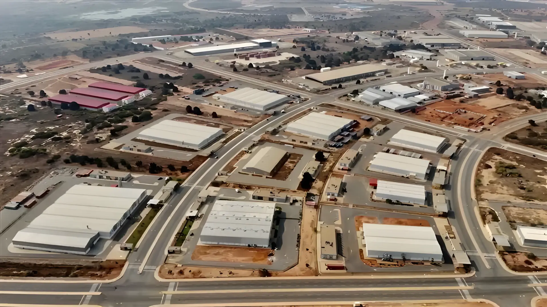 Vue aérienne d’entrepôts et de halls industriels le long d’un quadrillage routier dans une zone industrielle à l’est de Luanda